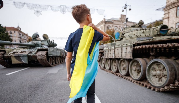 Menino segura bandeira em meio a Guerra da Ucrânia.