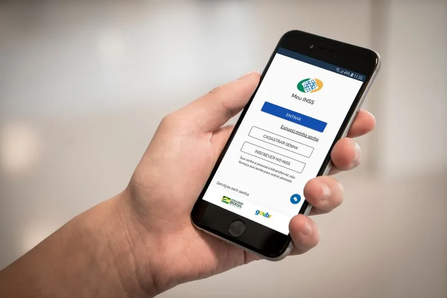 Pessoa segurando telefone celular com o aplicativo meu inss aberto