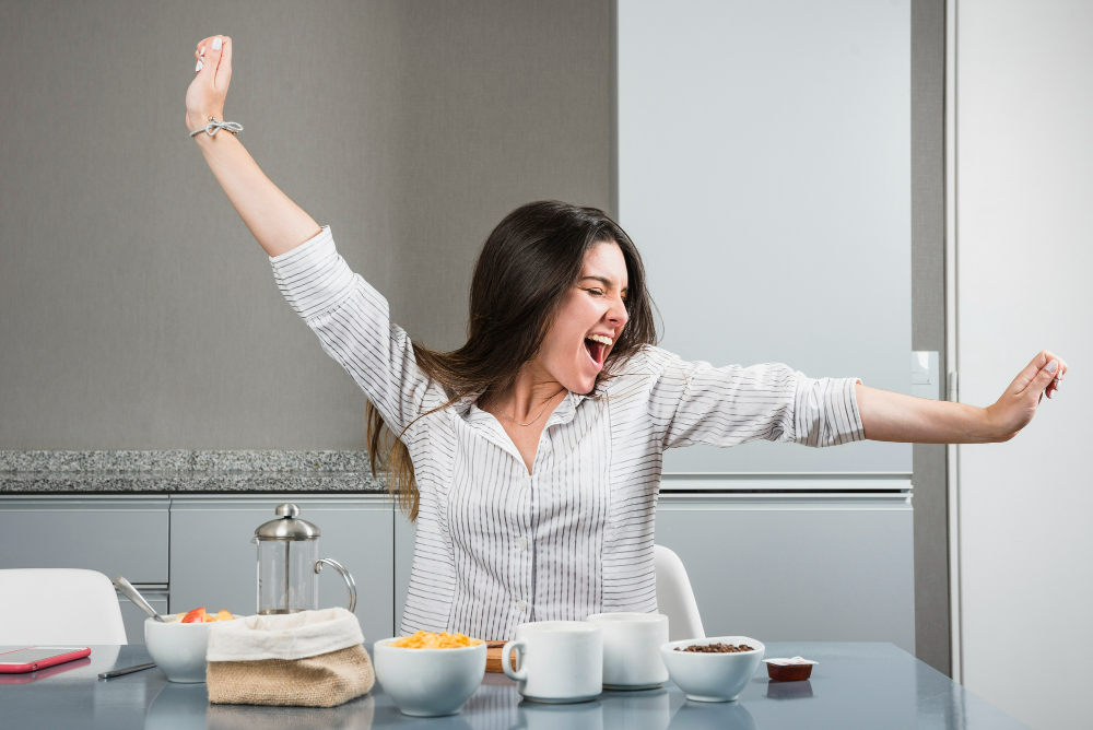 Mulher sorridente espreguiçando-se durante o café da manhã, transmitindo energia e positividade para começar o dia