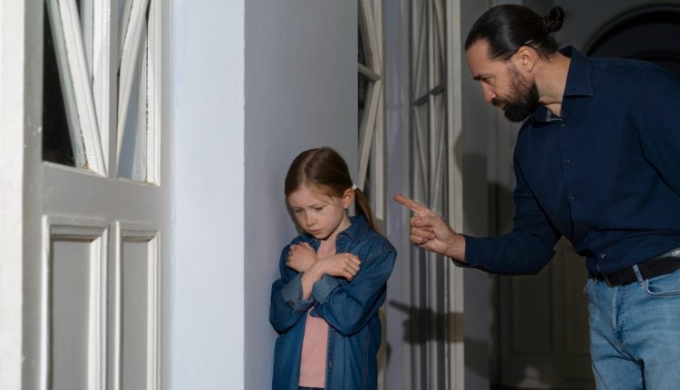 Homem num quarto falando como uma criança com braços cruzados sobre o peito