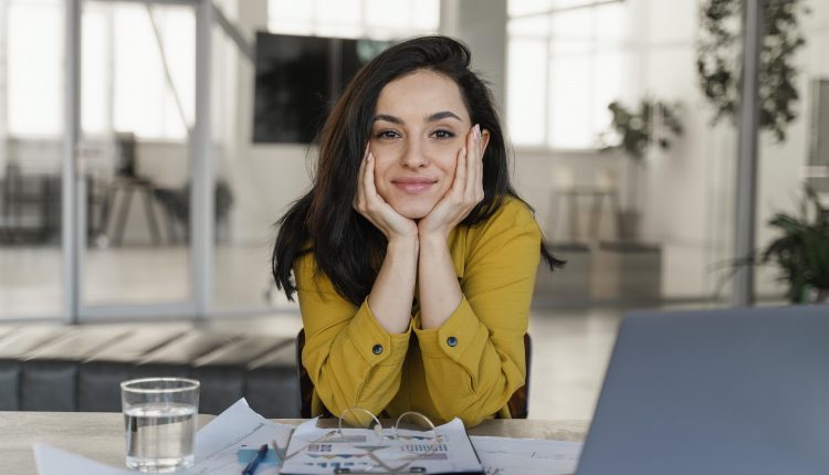 Mulher com braços sobre a mesa olhando para frente.