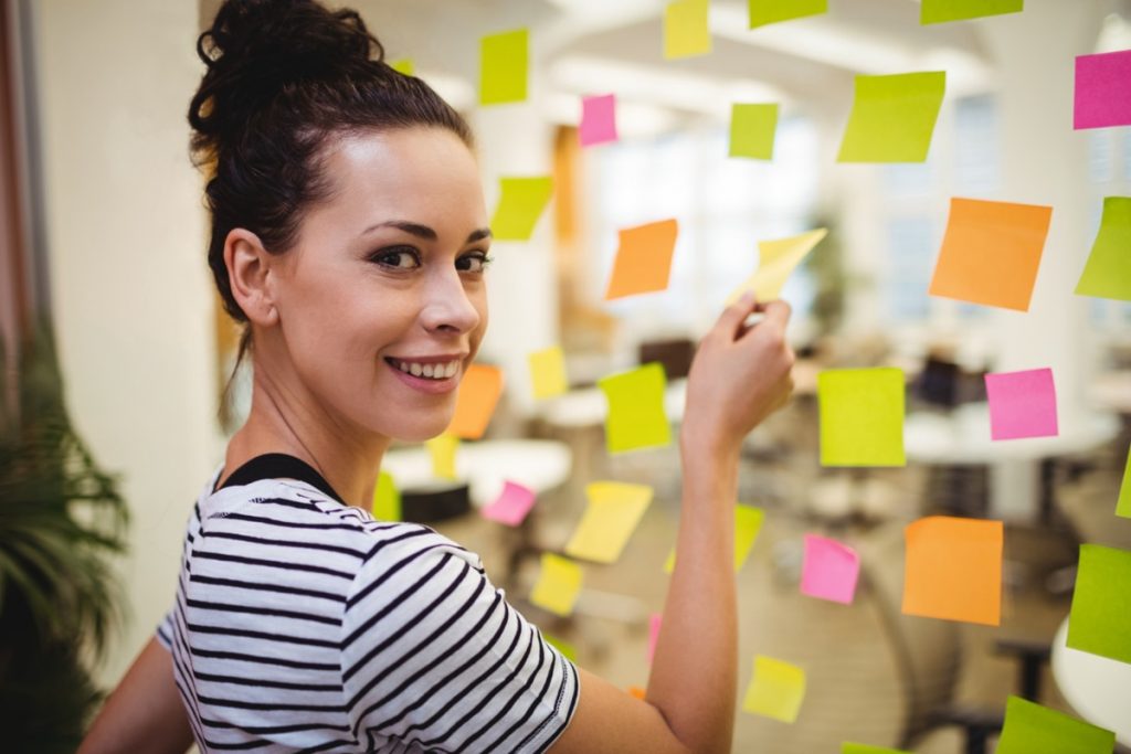 Mulher organizando tarefas com post-its coloridos