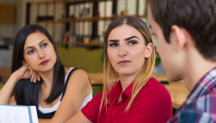 Grupo de pessoas em uma conversa, com expressões de desconfiança e análise.