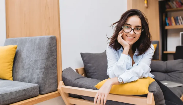 Mulher sorrindo em ambiente moderno e confortável, com expressão de confiança e inteligência