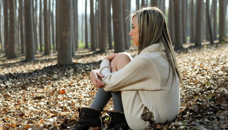 Mulher sentada em um ambiente natural, refletindo, em um momento de introspecção, representando o sentimento de estagnação.