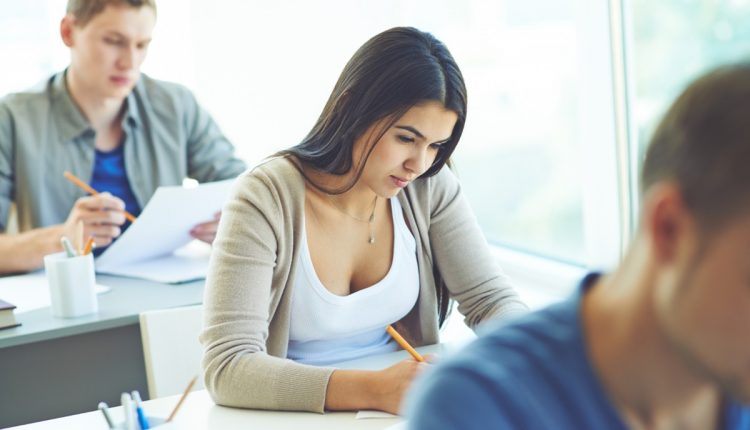 Jovem concentrada em prova, representando dedicação nos estudos para processo seletivo.