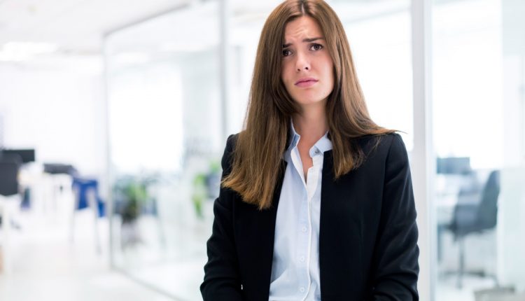 Mulher de expressão preocupada em um ambiente corporativo moderno.