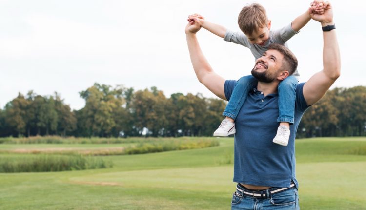 Pai e filho brincando ao ar livre, representando o vínculo paterno e a importância da paternidade na formação emocional da criança.