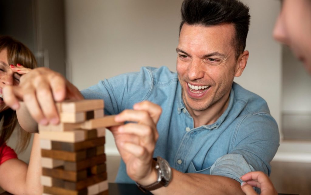 Homem sorrindo enquanto joga Jenga, simbolizando adaptação e tomada de decisão.