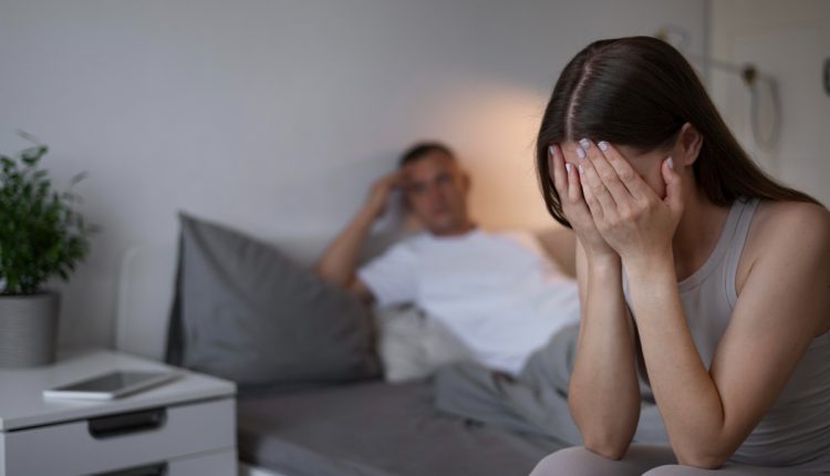 Mulher chorando com as mãos no rosto enquanto homem observa ao fundo, representando sinais de imaturidade emocional no relacionamento.