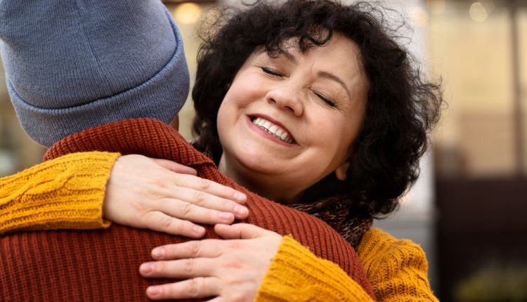 Mulher sorrindo enquanto abraça alguém, representando empatia e bondade nas relações