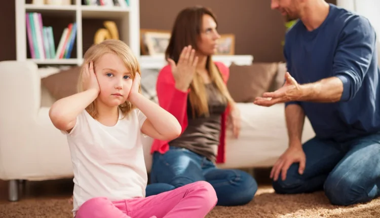 Criança cobrindo os ouvidos durante uma discussão entre os pais