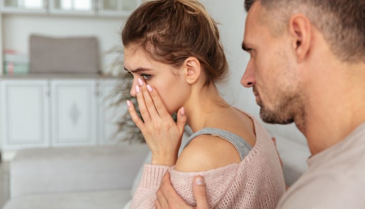 Mulher mostrando sinais de desconforto emocional durante uma discussão, enquanto é apoiada por outra pessoa