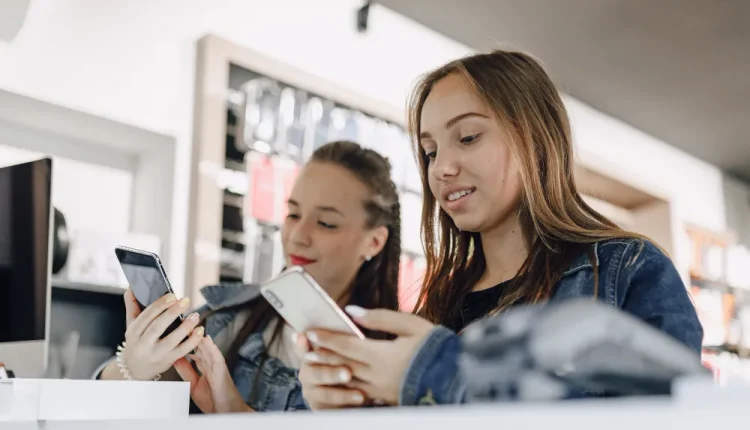 Jovens da Geração Z usando smartphones no ambiente de trabalho, representando o uso de tecnologia e foco no relaxamento.