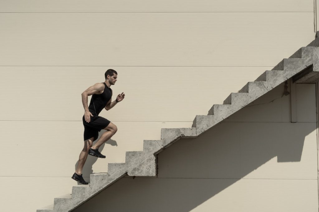 Homem correndo escada acima, representando disciplina e determinação.