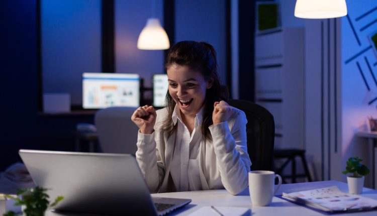 Profissional celebrando conquista no trabalho em ambiente corporativo moderno