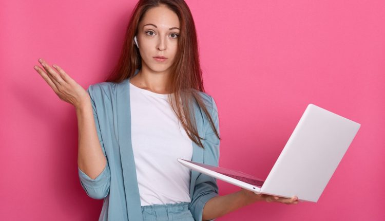 Mulher pensativa com laptop em mãos, representando dúvidas sobre abreviações formais em comunicações.