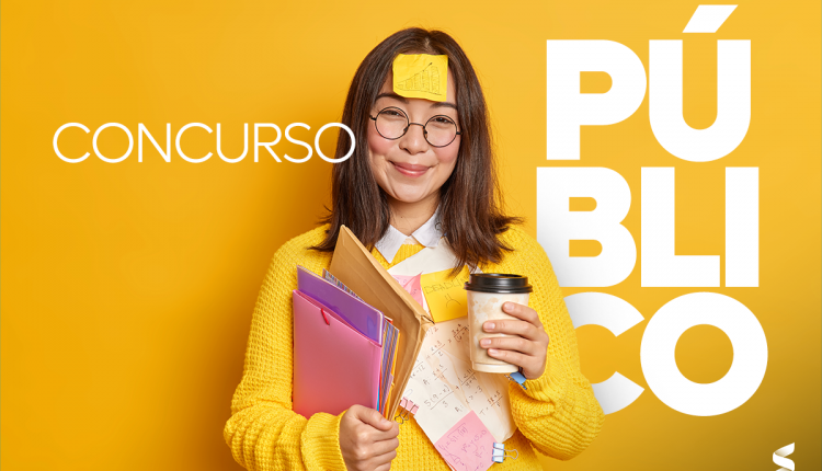 Mulher sorridente com óculos e roupa amarela segurando pastas e café, simbolizando preparação para concurso público.