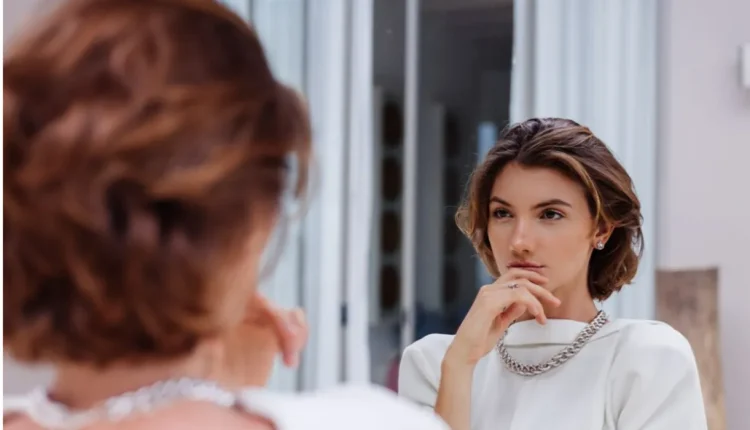 Mulher olhando para si mesma no espelho com expressão reflexiva, simbolizando autoconhecimento e autoestima