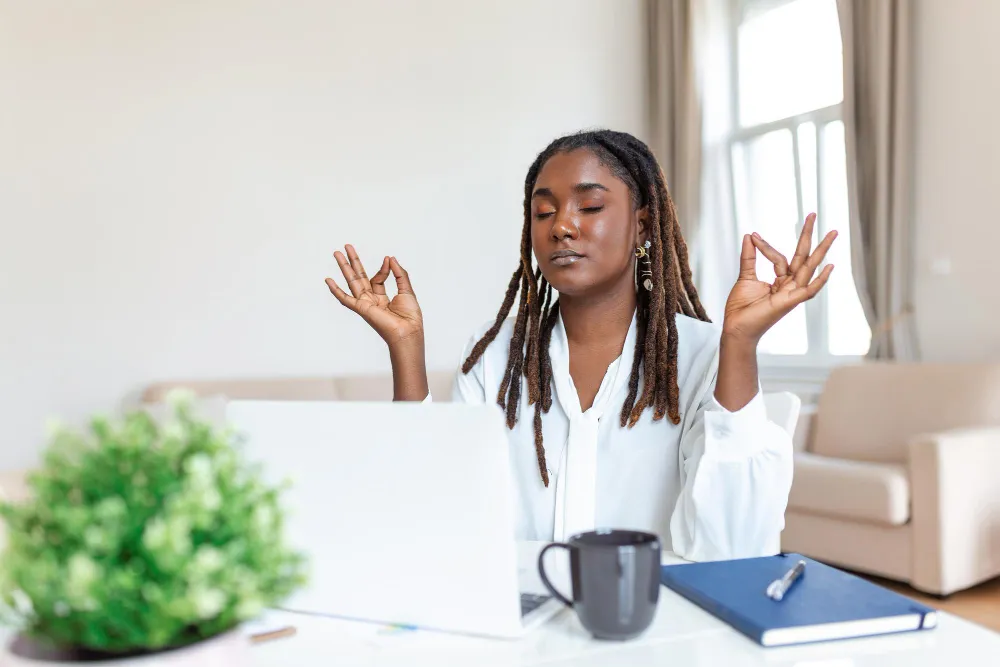 Pessoa praticando meditação enquanto trabalha no computador, simbolizando o uso de mindfulness para desenvolver inteligência emocional