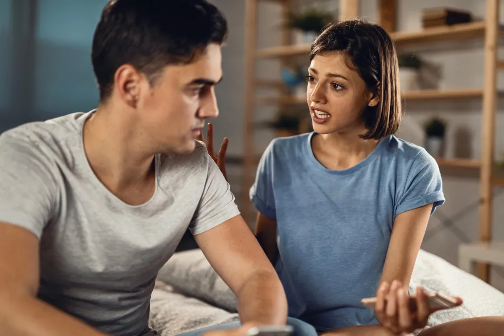 Mulher conversando com parceiro desatento, representando a falta de tempo no relacionamento.