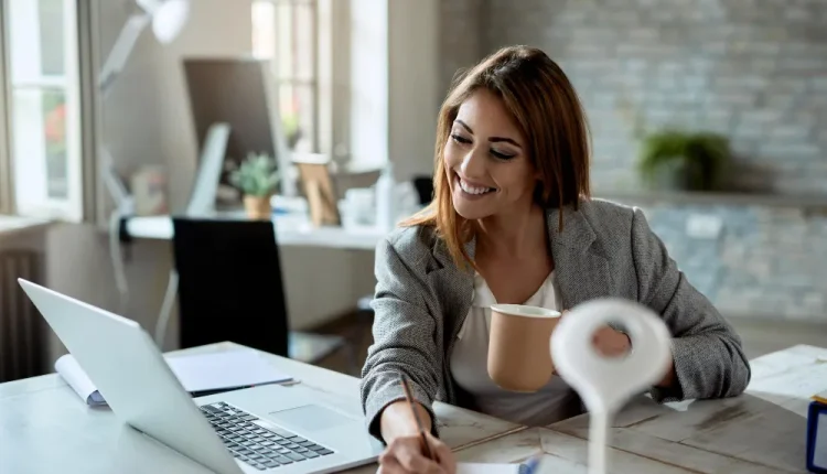 Mulher sorrindo enquanto anota algo em um caderno, representando positividade e mentalidade resiliente