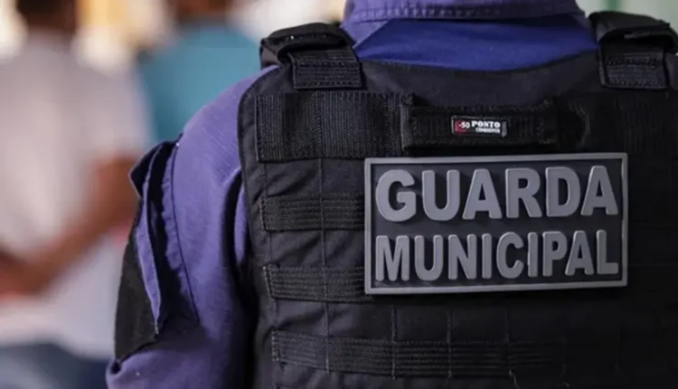 Detalhe do uniforme de um agente da Guarda Municipal com colete tático e identificação.