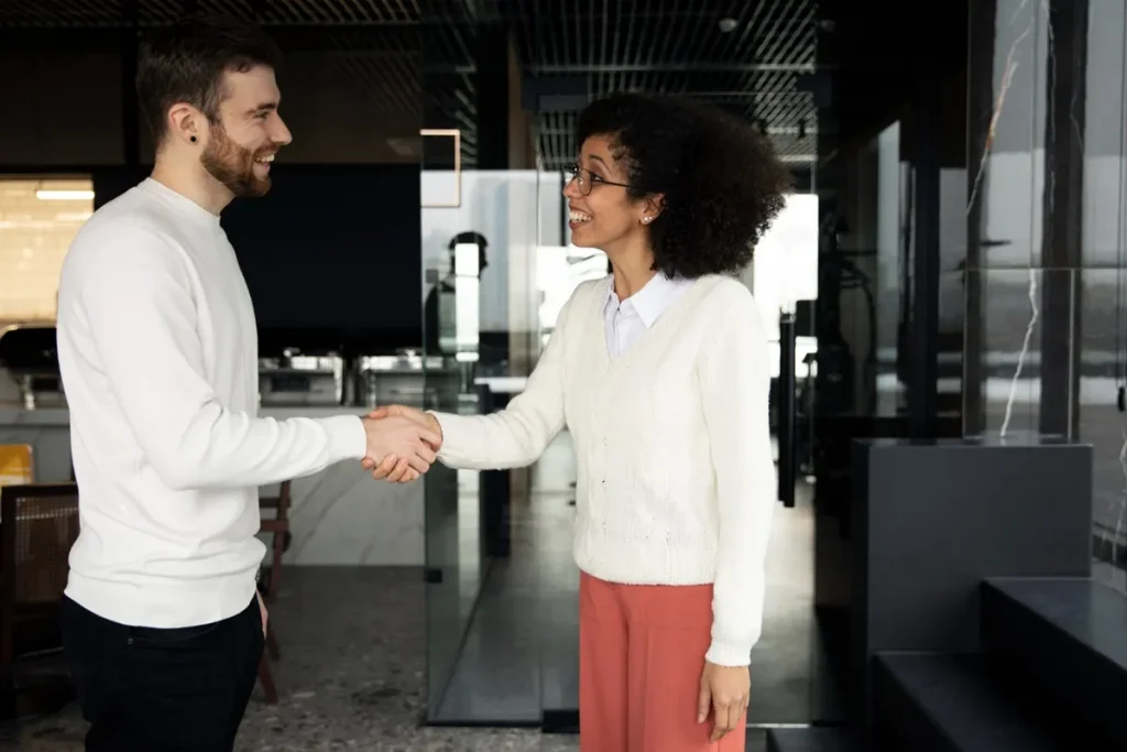 Duas pessoas cumprimentando-se com um aperto de mão, destacando o impacto nas primeiras impressões.