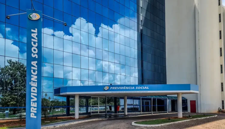 Fachada espelhada do prédio da Previdência Social com céu refletido nas janelas.