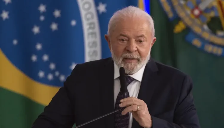 Presidente Lula discursa durante evento oficial, com bandeira do Brasil ao fundo