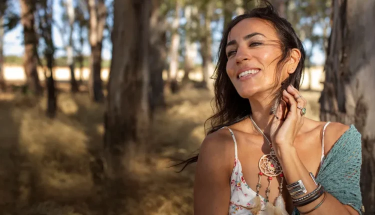 Mulher sorridente em meio à natureza, representando leveza e transformação pessoal.