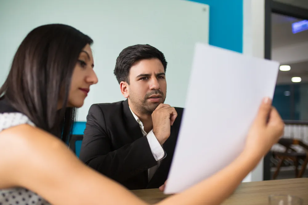 Homem e mulher analisando documento, simbolizando a resiliência diante de críticas e feedbacks construtivos