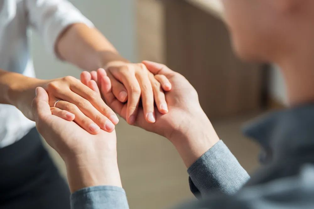 Duas pessoas segurando as mãos, representando empatia e validação emocional.