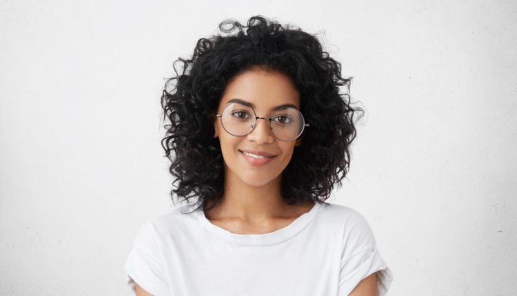 Mulher sorrindo com óculos, representando a inteligência e os traços de personalidade destacados pela psicologia.