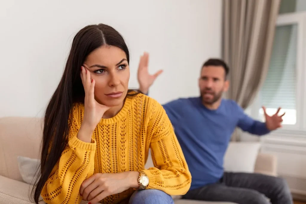 Mulher exausta, ouvindo um homem em discussão, refletindo uma fase de desconexão e diferenças de perspectivas em um relacionamento.