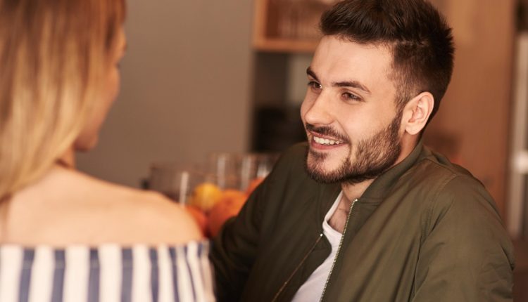 Homem sorrindo e conversando de forma envolvente com uma mulher.