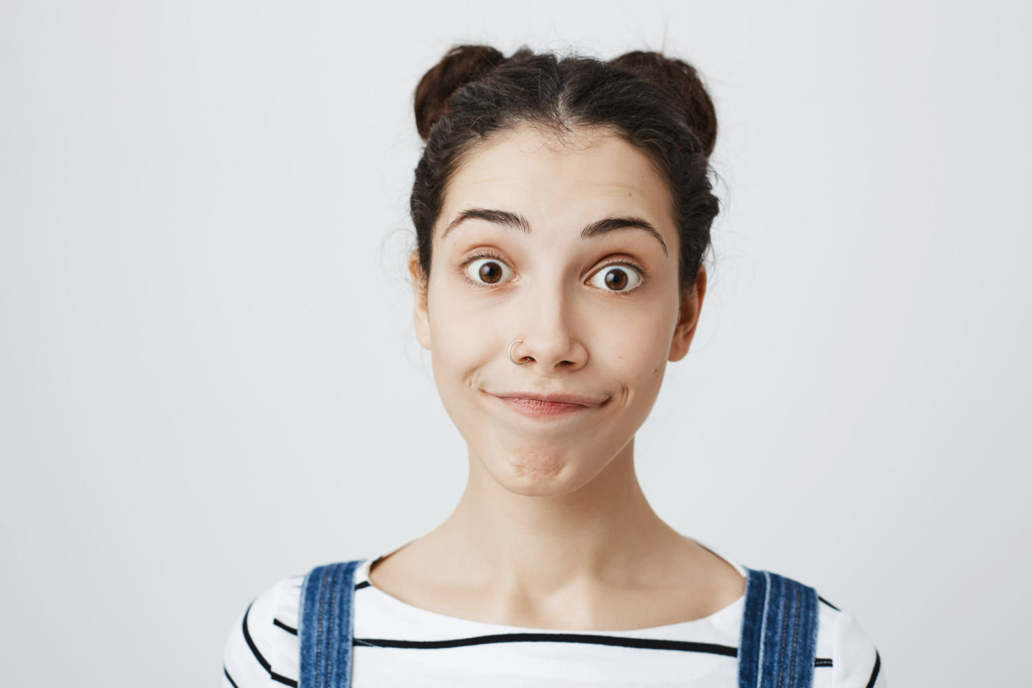 Mulher com expressão de confusão ou surpresa, com cabelo preso em dois coquezinhos e blusa listrada.