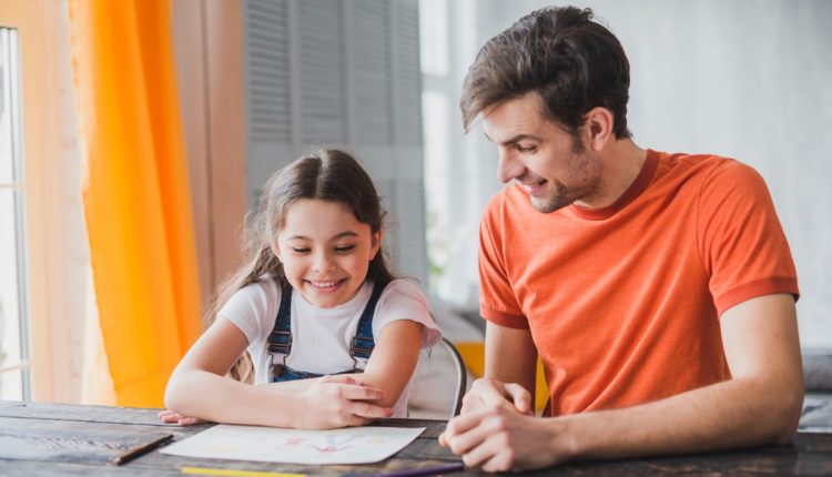 Pai e filha estudando juntos, sorrindo e interagindo positivamente