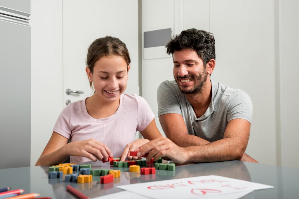 Pai e filha brincando com blocos educativos, sorrindo e aprendendo juntos