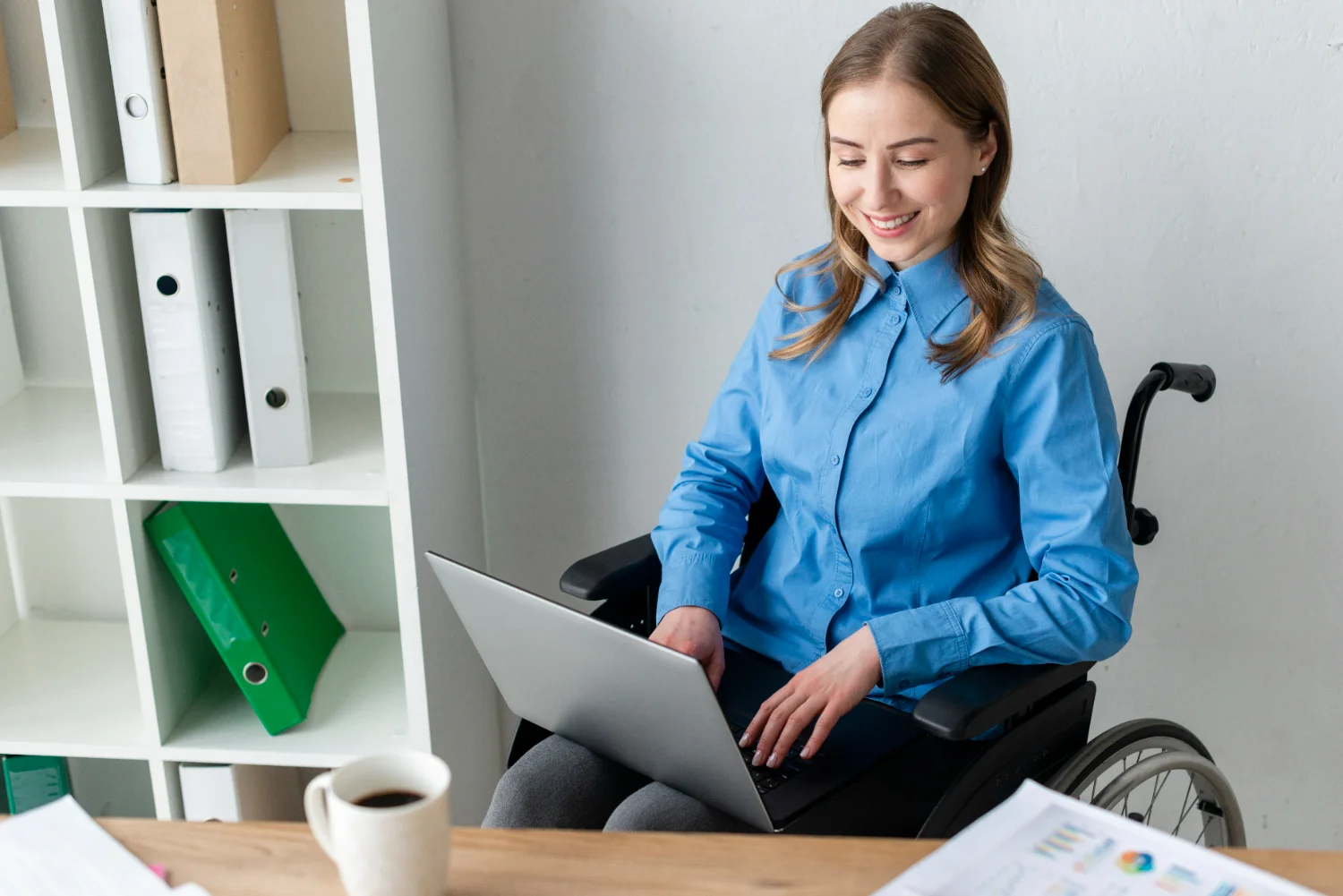 Mulher em cadeira de rodas trabalhando em um laptop.