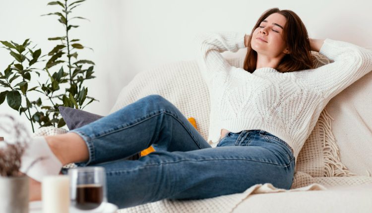 Mulher relaxando no sofá com expressão de tranquilidade e satisfação.