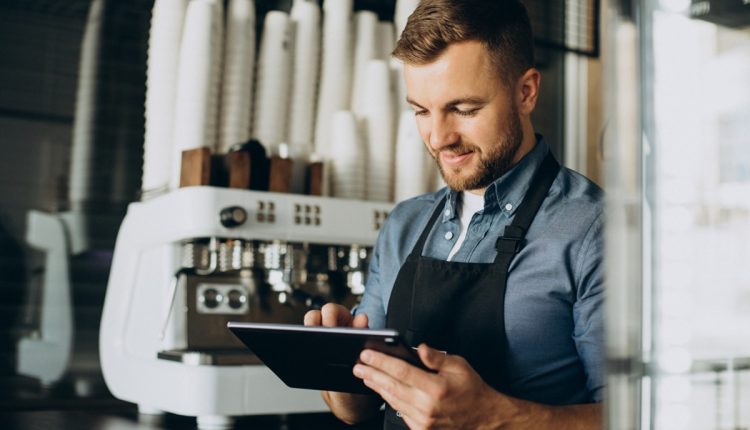 Barista sorridente usando tablet em cafeteria moderna