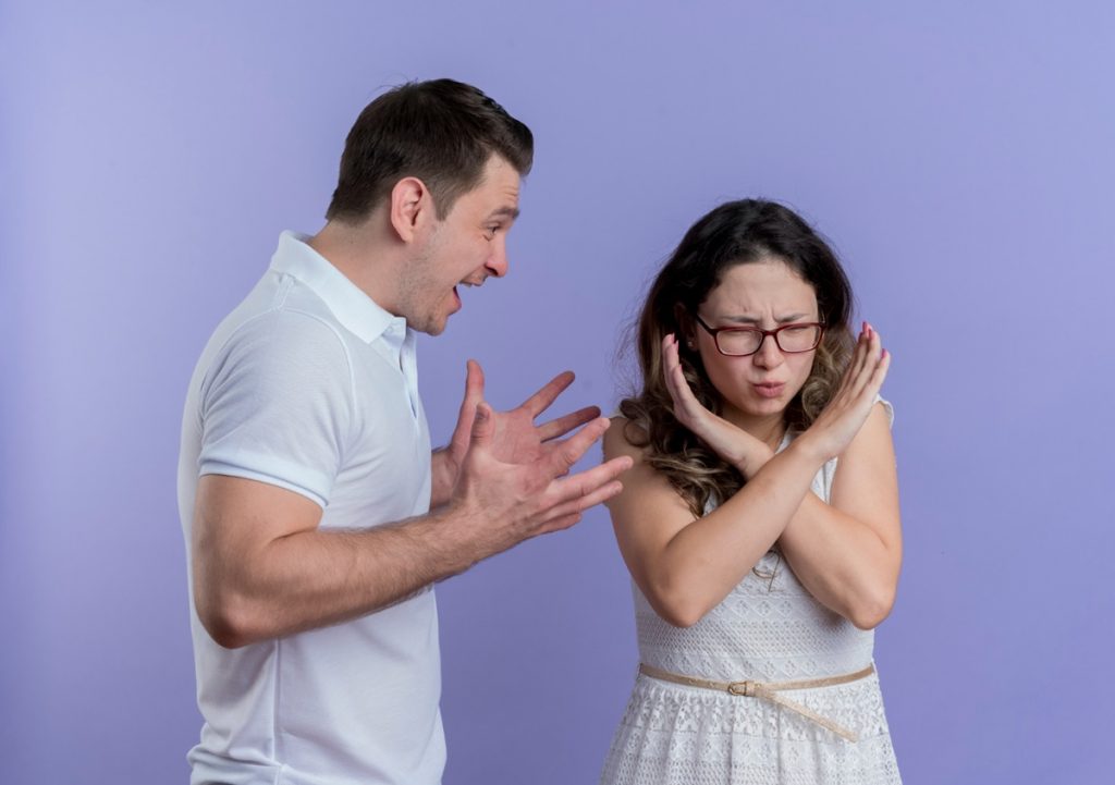 Homem exaltado discutindo com uma mulher que se protege com os braços cruzados, representando um possível caso de gaslighting.