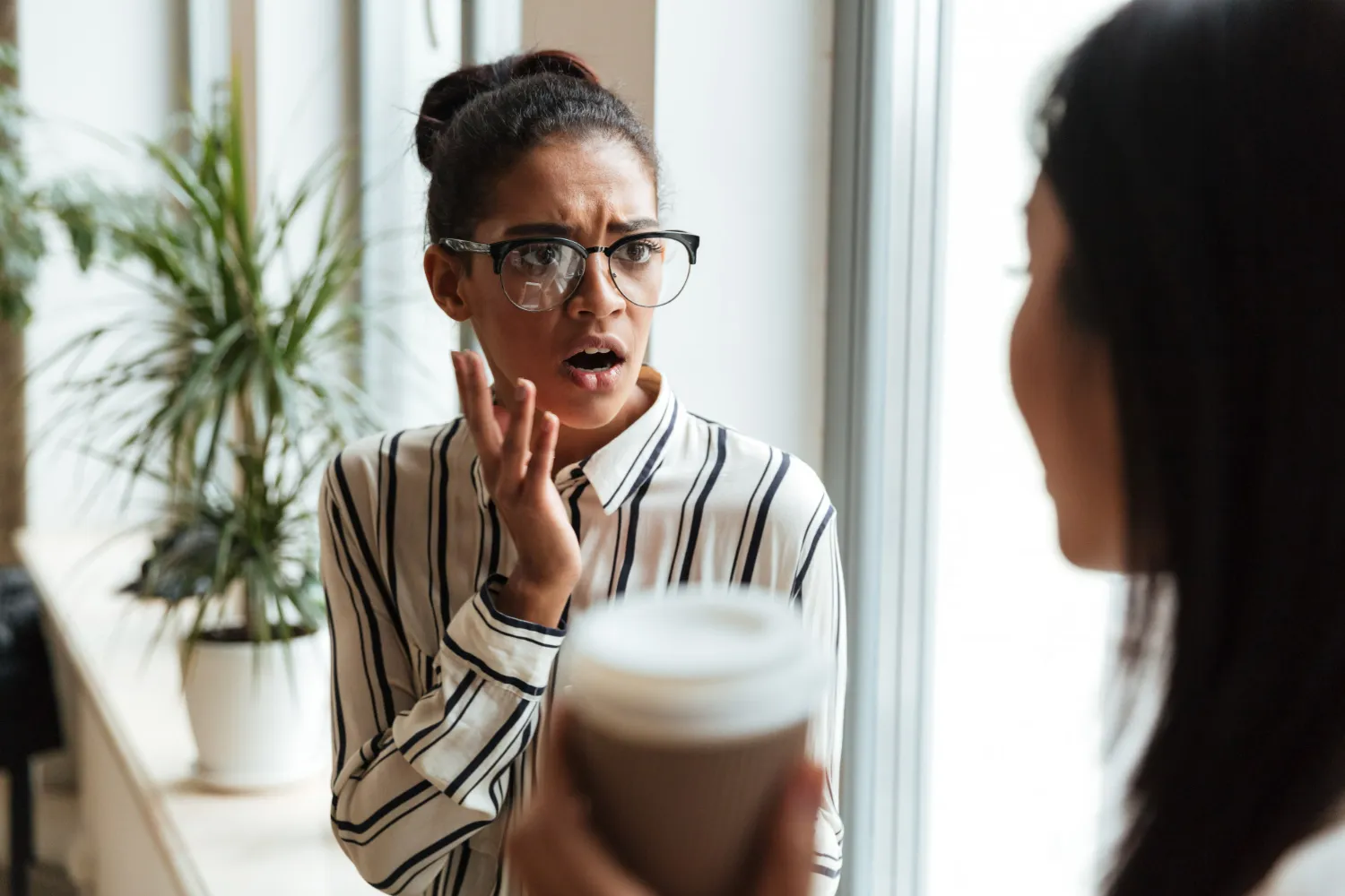 Mulher com expressão surpresa e preocupada ouvindo outra pessoa, simbolizando uma reação emocional em uma conversa.