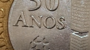 Erro de cunhagem na moeda comemorativa de 50 anos do Banco Central, com a letra "S" da palavra "ANOS" marcada.