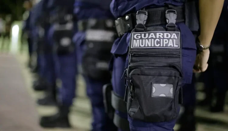 Imagem de Guardas Municipais alinhados, destacando o uniforme e a placa de identificação, relacionada ao concurso com inscrições prorrogadas.