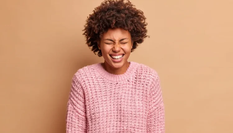 Mulher sorrindo com expressão de riso incontrolável.