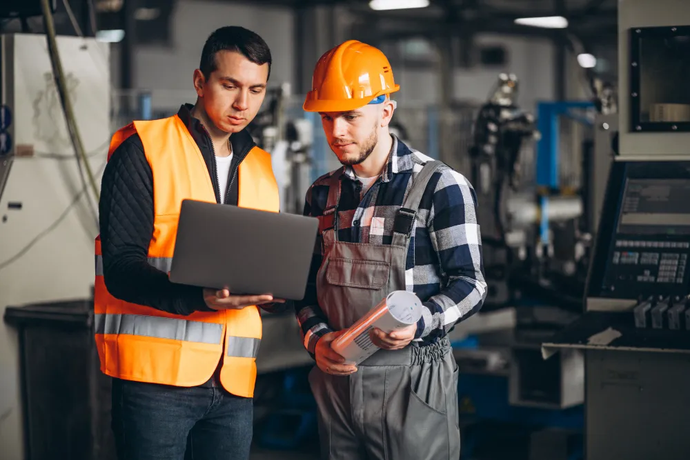 Dois engenheiros em ambiente industrial discutindo projetos e inovações, simbolizando a importância dos engenheiros mecânicos.