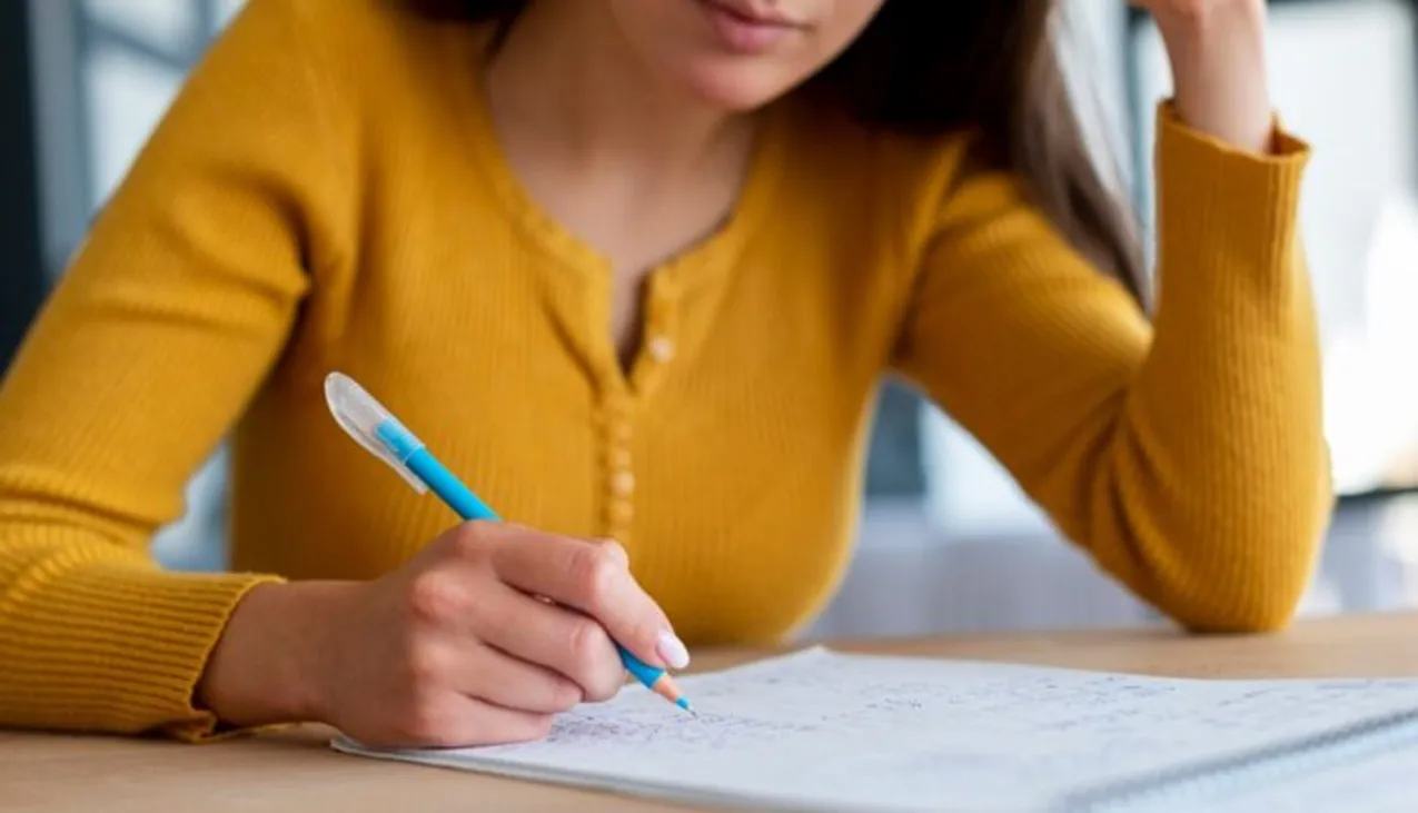 Mulher estudando com caderno e lápis, se preparando para um concurso público.