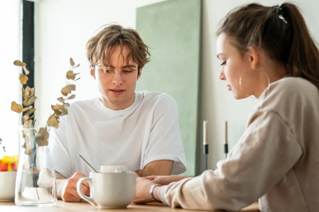 Homem olhando para baixo enquanto conversa com uma mulher, evitando contato visual.